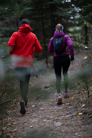 trail running with a sporty couple in the magic forest in early morningの写真素材