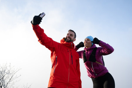 couple of hikers or track runners taking a selfie on the top of the mountainの写真素材