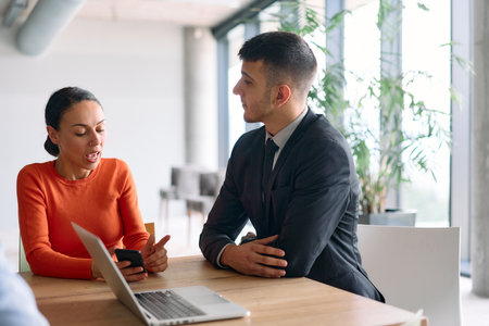 A young, diverse business team sitting together in a modern office, exchanging ideas and business plans, fostering collaboration and innovation for future success.の写真素材