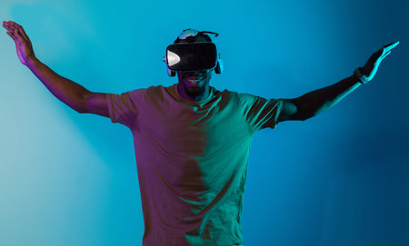 African American man dons VR glasses, engrossed in a virtual reality simulation, gesturing with...