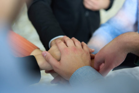 A top view of business people joining hands in a circle, symbolizing unity, collaboration, and...