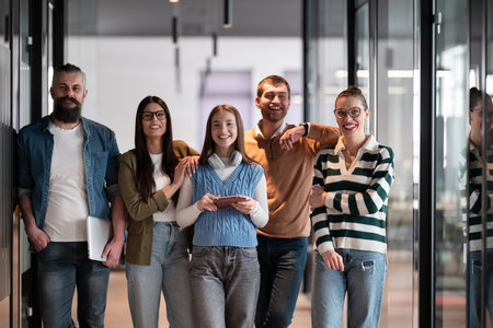 A diverse team of professionals in a modern coworking startup office smiles together, showcasing teamwork, collaboration, and a positive corporate culture that promotes innovation and a dynamic work environment.の写真素材