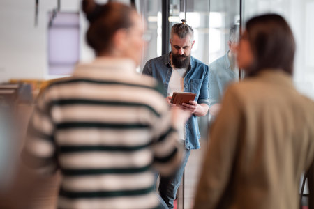 Bearded businessman, IT professional, trader, and crypto investor using a digital tablet in a modern coworking space. Tech-savvy professional working in an open office startup environmentの写真素材