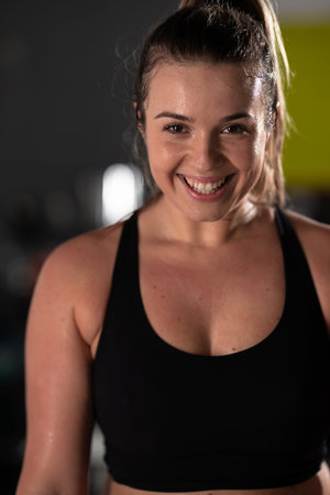 A beautiful and fit woman sitting on a gym ball with a towel, resting and recovering after an intense workout.の写真素材