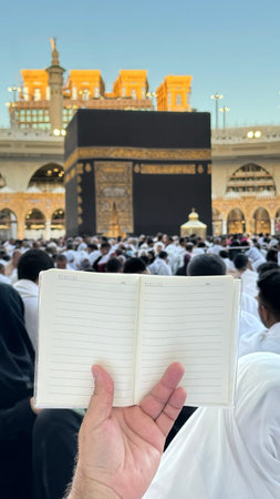 A pilgrim holds a small notebook with a heart doodle in front of the Kaaba in Mecca, Saudi Arabia....