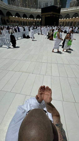 A bald man poses for a photo in front of the Kaaba at noon after performing Umrah at Masjid...