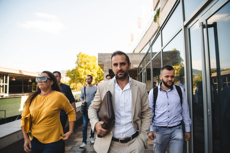 A diverse group of businessmen and colleagues walking together by their workplace, showcasing...