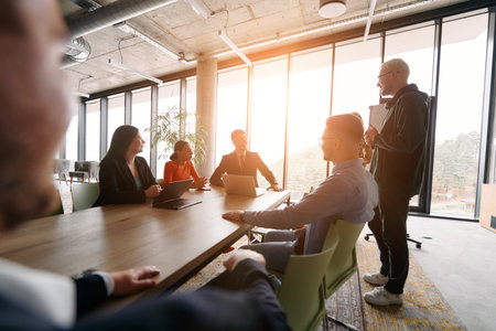 A diverse multiethnic business team engages in a collaborative meeting, discussing strategies and solutions in a modern office settingの写真素材