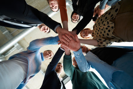 A group of business professionals, captured from a low angle, holding hands to symbolize unity and teamwork.の写真素材