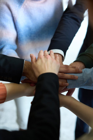 A top view of business people joining hands in a circle, symbolizing unity, collaboration, and shared success in the workplaceの写真素材