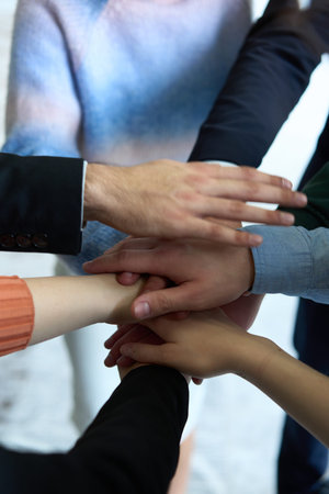A top view of business people joining hands in a circle, symbolizing unity, collaboration, and...