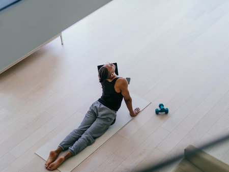 Training At Home. Sporty man doing the training while watching an online tutorial on a laptop, exercising in the living room, free space.の写真素材