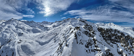 A breathtaking aerial view of a beautiful winter landscape with snow-covered alpine mountains, sunny...