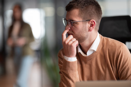 Scene of a businessman putting a finger in his nose. Employee in the office, thinking and brainstorming ideas for a startup. Man at workplace working on laptop, copywriting and innovation in a creative agency workspace.の写真素材