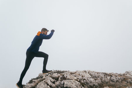 Man Climbing Rocky Hill in Fog