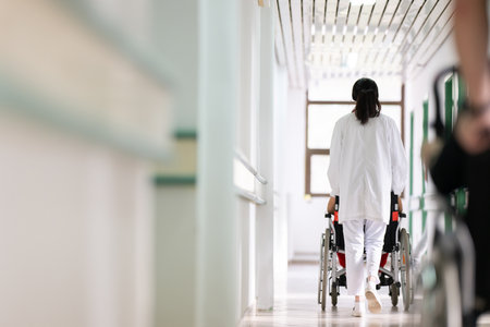 Young Male Patient in Wheelchair Assisted by Female Medical Professionalの写真素材