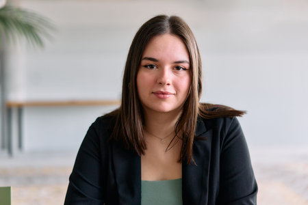 A close up portrait of a young businesswoman engaged in a professional meeting, confidently...
