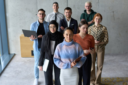A diverse and determined team of business professionals stands confidently in an office, ready to tackle new business plans and challenges with a focus on success and growthの写真素材
