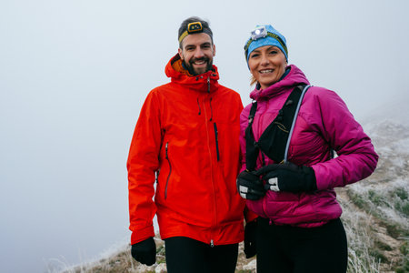 Hikers Posing on Foggy Mountain Top.Portrait of two hikers posing together on a foggy mountain top wearing outdoor gear.の写真素材