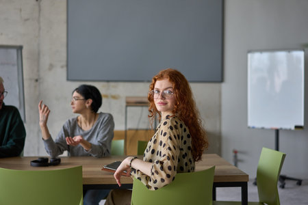 A young, diverse business team sitting together in a modern office, exchanging ideas and business...