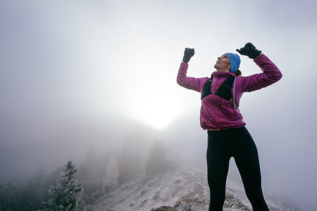 Woman Celebrating at Mountain Summit.Woman celebrating on rocky mountaintop with arms raised in...