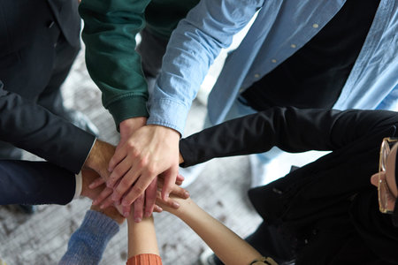 A top view of business people joining hands in a circle, symbolizing unity, collaboration, and shared success in the workplaceの写真素材