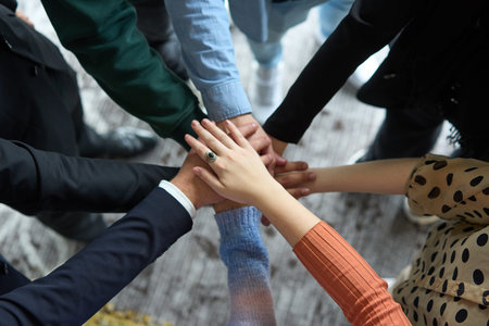 A top view of business people joining hands in a circle, symbolizing unity, collaboration, and...
