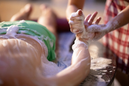 Hand Foam Therapy. Attendant gently washing patient hands with foamy soap in traditional bath setting.の写真素材