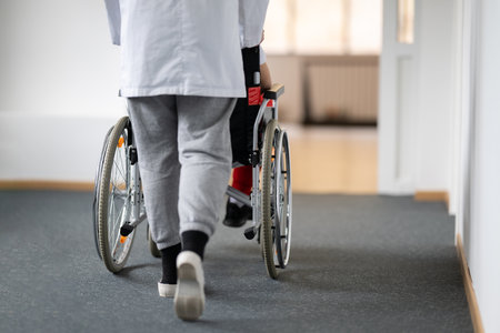 Young Male Patient in Wheelchair Assisted by Female Medical Professionalの写真素材