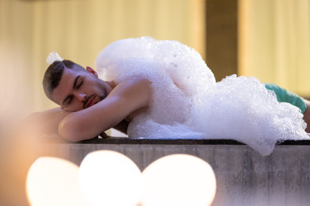 Man Relaxing in Foam.Relaxed man lying in Turkish bath covered in white foam during cleansing ritual.の写真素材