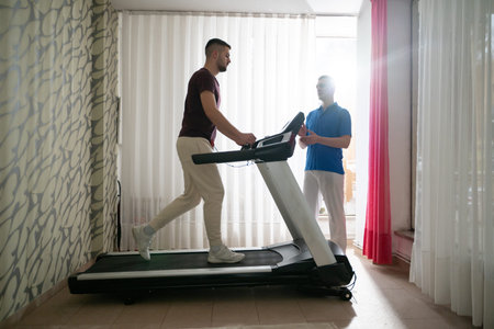 Physical Therapy on Treadmill.Man undergoing physical therapy with trainer assistance on a treadmill indoors.の写真素材
