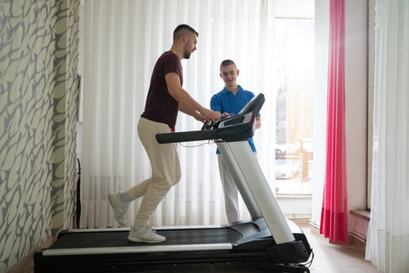 Physical Therapy on Treadmill.Man undergoing physical therapy with trainer assistance on a treadmill...