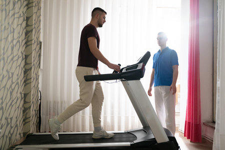 Physical Therapy on Treadmill.Man undergoing physical therapy with trainer assistance on a treadmill indoors.の写真素材