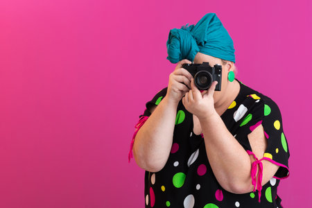 Playful woman aiming camera at viewer in studioの写真素材