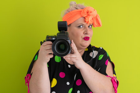 Colorful woman holding professional DSLR camera in studioの写真素材