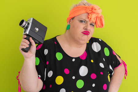 Unimpressed woman holding vintage camera with skeptical look