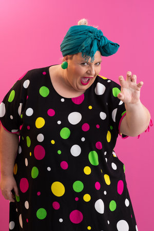 Colorful expressive big size woman posing in polka dot dress on pink backgroundの写真素材