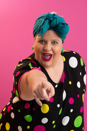 Colorful expressive big size woman posing in polka dot dress on pink backgroundの写真素材