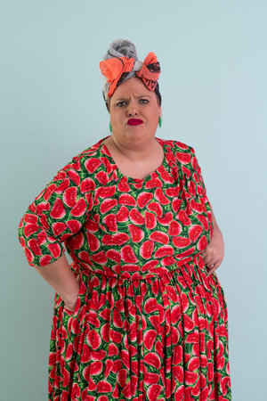 Unimpressed woman in watermelon dress posing with hands on hipsの写真素材
