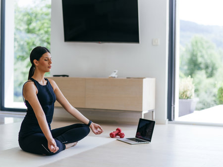 Young Beautiful Female Exercising, Stretching and Practising Yoga with Trainer via Video Call Conference in Bright Sunny House. Healthy Lifestyle, Wellbeing and Mindfulness Concept.の写真素材