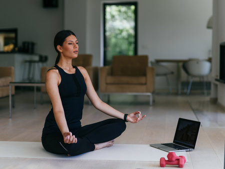 Young Beautiful Female Exercising, Stretching and Practising Yoga with Trainer via Video Call Conference in Bright Sunny House. Healthy Lifestyle, Wellbeing and Mindfulness Concept.の写真素材