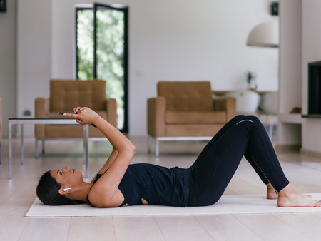 Woman resting after online training while lying on the living room floor.の写真素材