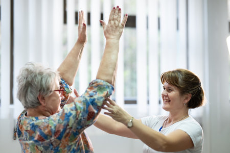 Senior Physical Therapy Session.Senior woman doing physical exercises with the help of a smiling therapist. Concept of elderly rehabilitation and movement recovery.の写真素材