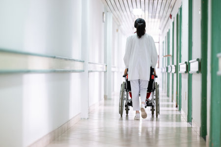 Young Male Patient in Wheelchair Assisted by Female Medical Professionalの写真素材