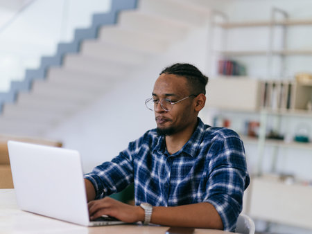 African American Man Calling While Working on Laptop