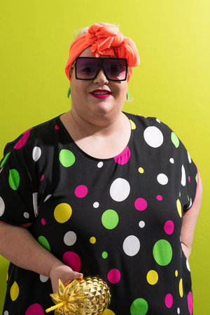 Smiling woman in oversized sunglasses holding golden pineapple