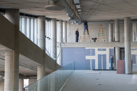 A team of workers collaborates to install a modern ventilation system within a building, carefully...