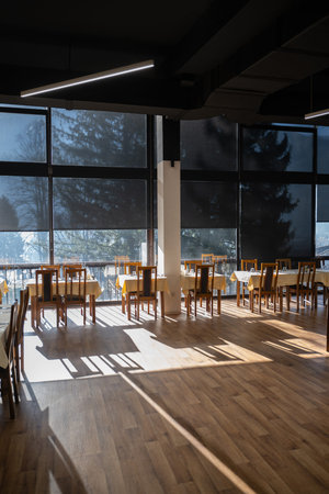 Restaurant interior with large sunlit windows and wooden chairs