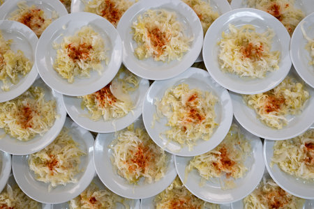 Overhead view of many plates filled with cabbage salad garnished with paprika, catering and food...