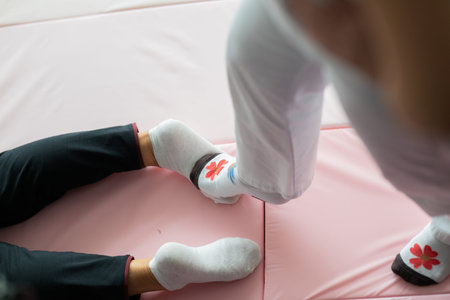 Close up of physiotherapist assisting an older woman by holding her legs during a rehabilitation...